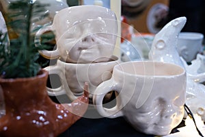 Handmade ceramic souvenirs. Clay cups with a human face.