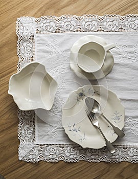 Handmade ceramic tableware in retro style - tea pair, bowl, plate, silver cutlery on a wooden table, top view