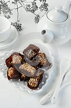 Handmade chocolate covered with cocoa and nut crumbs. Still life with sweets and tea appliances