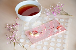 Handmade chocolate with fresh and dried fruits and cup of hot tea on light wooden table