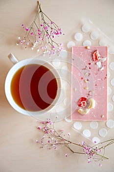 Handmade chocolate with fresh and dried fruits and cup of hot tea on light wooden table