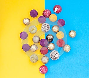 Handmade chocolate truffles, different colors on a blue and yellow background.