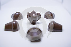 Handmade chocolates sweets in the shape of cups, cake and teapot on white background