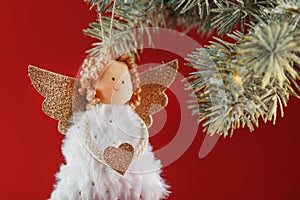 Handmade christmas angel toy on a Christmas tree on a red background