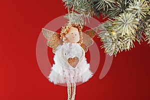 Handmade christmas angel toy on a Christmas tree on a red background