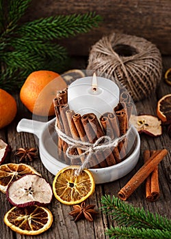 Handmade Christmas candle decorated with cinnamon sticks. Slices of fresh dried apple, orange and spices for cooking or baking.
