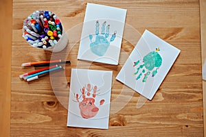 Handmade christmas handprints post cards and pencils on wooden table