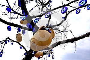 Handmade clay pitchers and greek blue evil eye hanging on tree