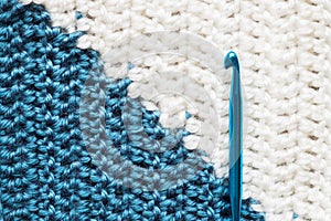 Handmade close-up simple blue and white crochet pattern with crochet hook
