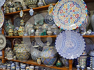 Handmade colourful decorated bowls, plates and cups on display at traditional souk - street market in Morocco