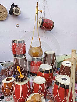 Handmade colourful musical instruments ,Dhol, Aktara & Duitara  displayed on a white background for sale.