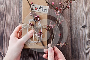 Handmade craft box gifts with painted vase and bouquet of spring branches and flowers in daughter`s hands on wooden background an