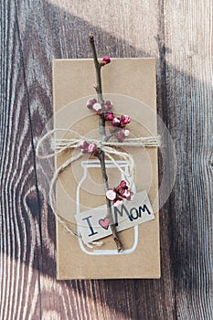 Handmade craft box gifts with painted vase and bouquet of spring branches and flowers on wooden background and text I love mom.