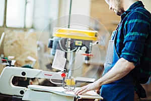 Carpenter engaged in processing wood at the sawmill.