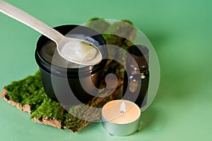 Handmade Cream with Organic Essential Oil Moisturizing Cream for the Skin on Tree Bark with Moss Burning Candle Green Background