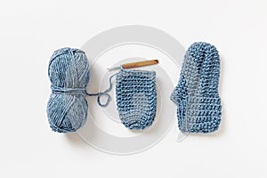 Handmade crochet cozy slippers with crochet hook and ball of yarn.