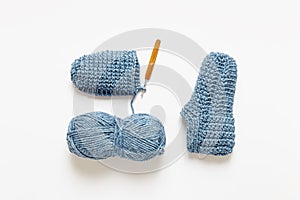 Handmade crochet cozy slippers with crochet hook and ball of yarn.