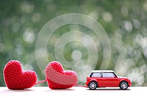Handmade crochet heart and miniature car on natural green background for valentine day and wedding card