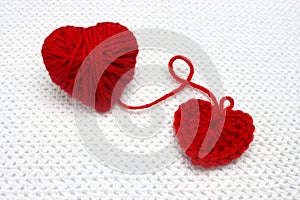 Handmade crochet heart and red yarn ball like a heart on the white crochet background. Red heart made of wool yarn. Romantic Chris