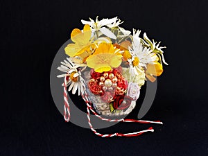Handmade crocheted basket with spring flowers and red and white string, known as Martisor.
