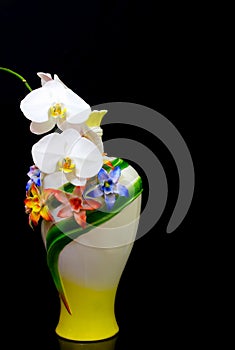 Handmade decorative porcelain vase with white phalaenopsis orchids against dark background