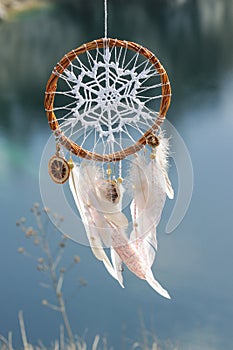Handmade dream catcher with white doily on background of rocks a
