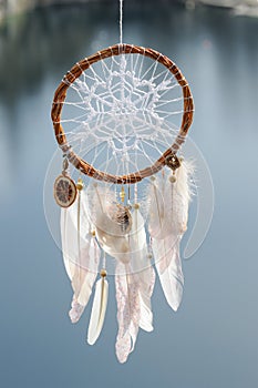 Handmade dream catcher with white doily on background of rocks a