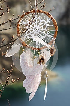 Handmade dream catcher with white doily on background of rocks a