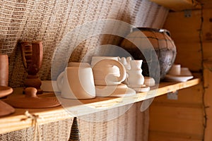 Handmade earthenware on a shelf in a store. Pot, bowl, plate, clay mug.