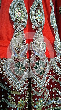Handmade embroidery with beads, precious stones, expensive gold threads on red fabric. Element of Indian Traditional National