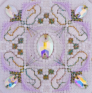 A handmade embroidery with white, purple and gold - green threads, white beads and crystals on it. 2