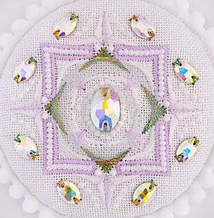 A handmade embroidery with white, purple and gold - green threads, white beads and crystals on it. 5