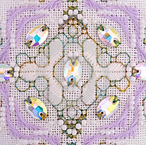 A handmade embroidery with white, purple and gold - green threads, white beads and crystals on it. 7. This ornament was