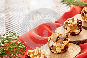 Handmade energy balls are lying on wooden saw cuts on red fabric on wooden table.