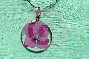 Handmade epoxy resin jewelry. pendant, hydrangea in copper frame. dried flowers. herbarium, oshibana. on green