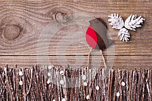 Handmade from felt bird robin on wooden background. Craft arranged from sticks, twigs, driftwood and pine cones white and shiny.