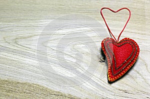 Handmade felt heart decorated with beads on wooden background.