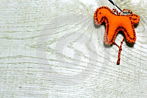 Handmade felt horse decorated with beads on wooden background.