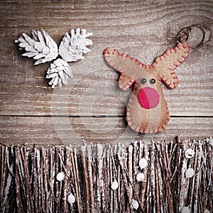 Handmade from felt Rudolph reindeer on wooden background. Craft