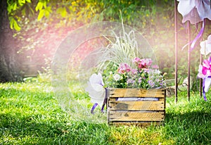 Handmade flowerbed with beautiful colored flowers inside, standing on the lawn in the park on a background blurred natural land