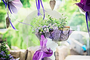 Handmade flowerbed with beautiful colored flowers inside, standing on the lawn in the park on background of blurred natural land