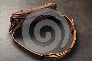 Handmade genuine brown leather on a dark background Brown belt bag. Elegant brown bag with a zipper