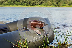Handmade genuine leather patronage rests on a rubber boat. Accessories for hunting and outdoor recreation. DIY saddlery