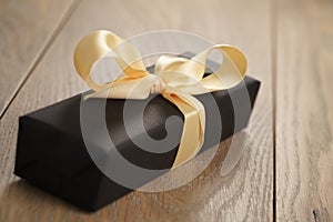 Handmade gift black paper box with yellow ribbon bow on wood table