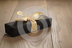 Handmade gift black paper box with yellow ribbon bow on wood table