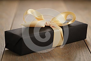 Handmade gift black paper box with yellow ribbon bow on wood table