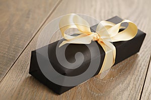 Handmade gift black paper box with yellow ribbon bow on wood table