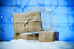 Handmade gift boxes from craft paper over snowy wooden table in blue light.