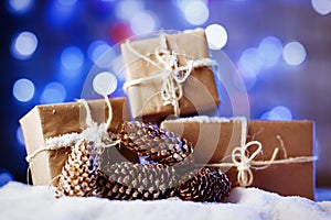 Handmade gift boxes from craft paper over snowy wooden table in blue light.