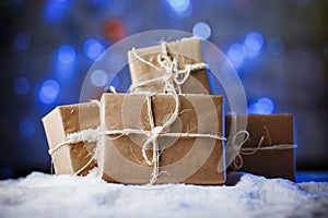 Handmade gift boxes from craft paper over snowy wooden table in blue light.